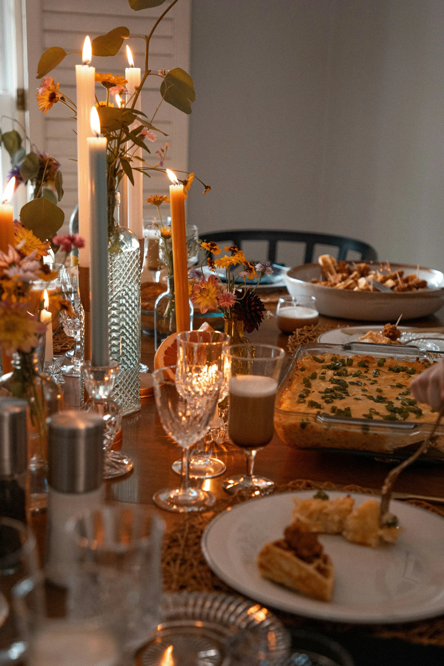 A generous dining table with flowers, candles and shared dishes