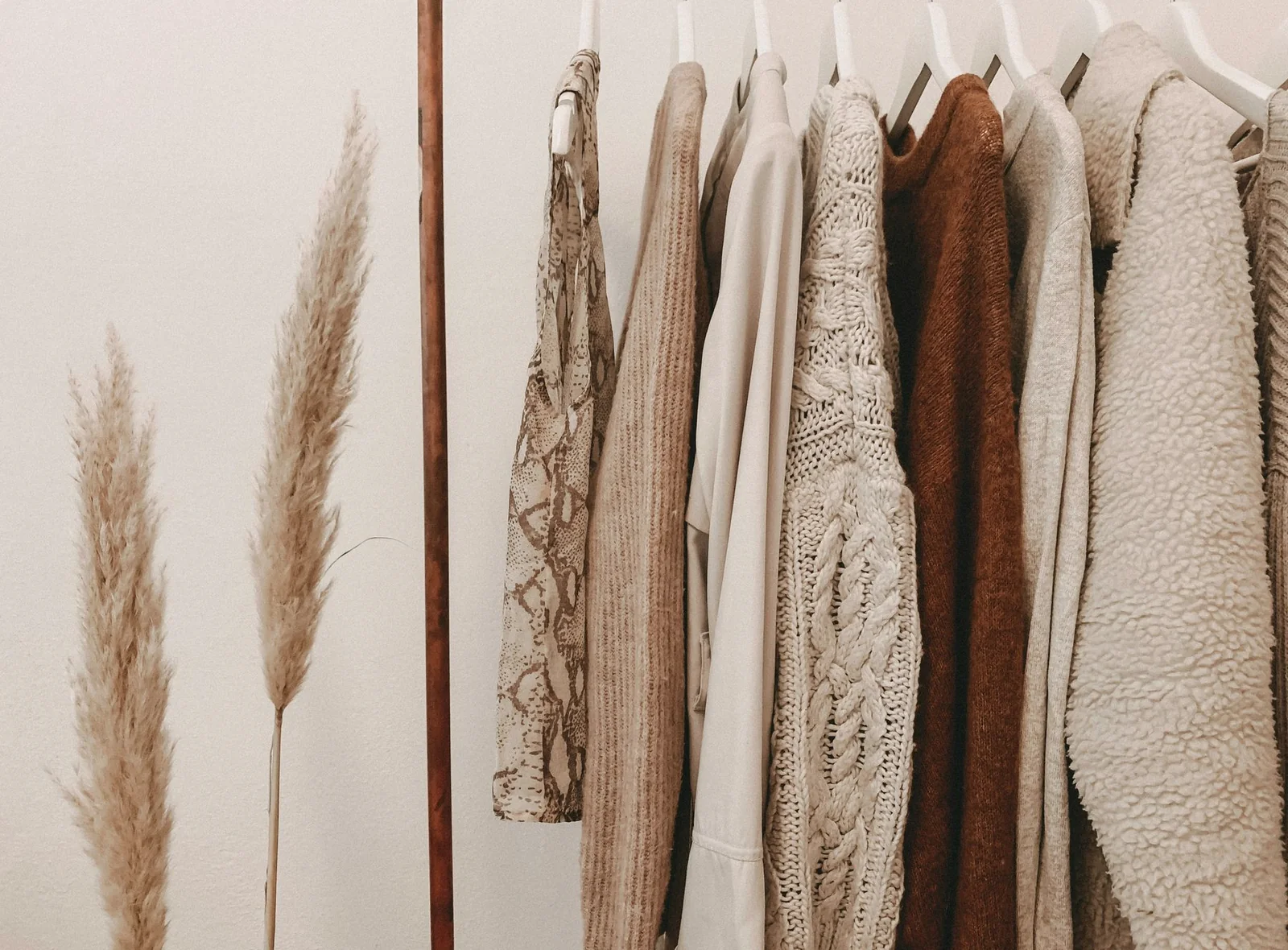 A considered wardrobe of natural-toned knitwear and layers on a clothing rail