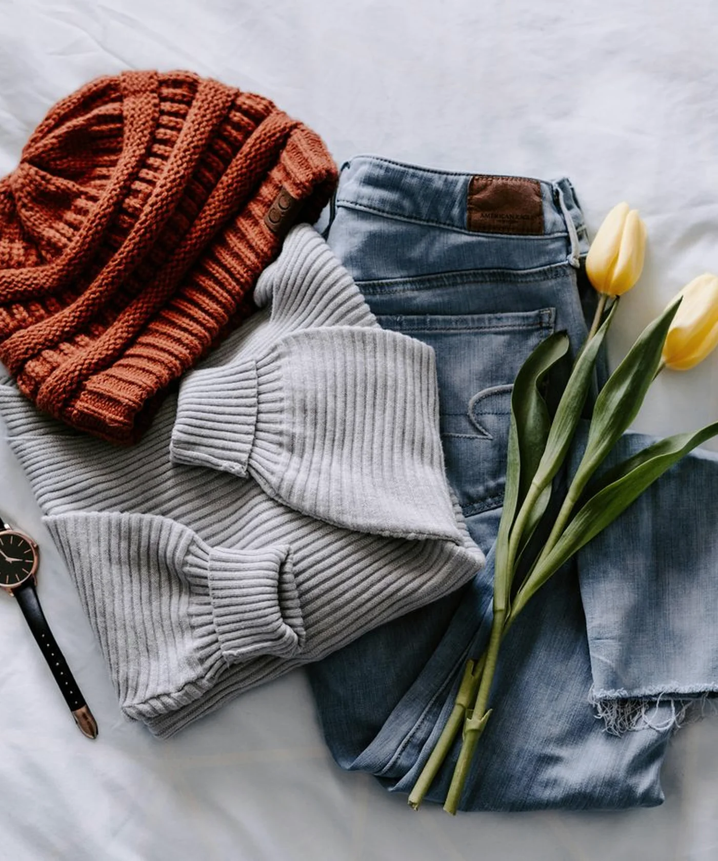 A casual capsule outfit arranged with a knit, denim and rust beanie